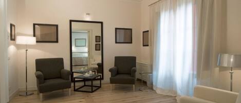 A living room with two armchairs, a coffee table, a floor lamp, and a mirror on the wall.