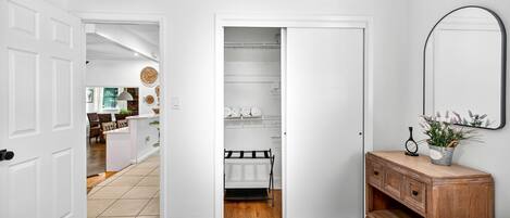 A bedroom with two beds, a wooden dresser, a mirror, and a closet with shelves.