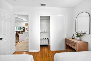 Ein Schlafzimmer mit zwei Betten, einem hölzernen Schminktisch, einem Spiegel und einem Kleiderschrank mit Einlegeböden.
