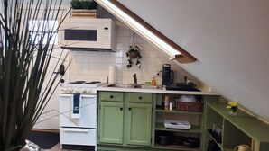 Una cocina con electrodomésticos blancos, armarios verdes y techo de madera.
