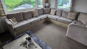 A living room with a sectional sofa, a rug, and a dog. - Ty-dee Holiday Home Inside Polperro Holiday (Looe)