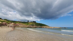 A beach with clear water, people walking, and hills in the background. - Ty-dee Holiday Home Inside Polperro Holiday (Looe)
