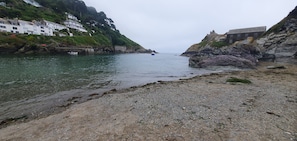 A coastal scene with a rocky shoreline, a calm sea, and buildings on the hillside. - Ty-dee Holiday Home Inside Polperro Holiday (Looe)