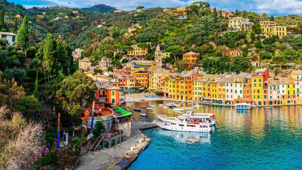 A coastal town with colorful buildings, a marina, and a hillside backdrop.