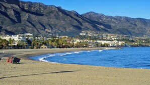 Eine Küstenstadt mit Strand, Bergen und Wohnhäusern.