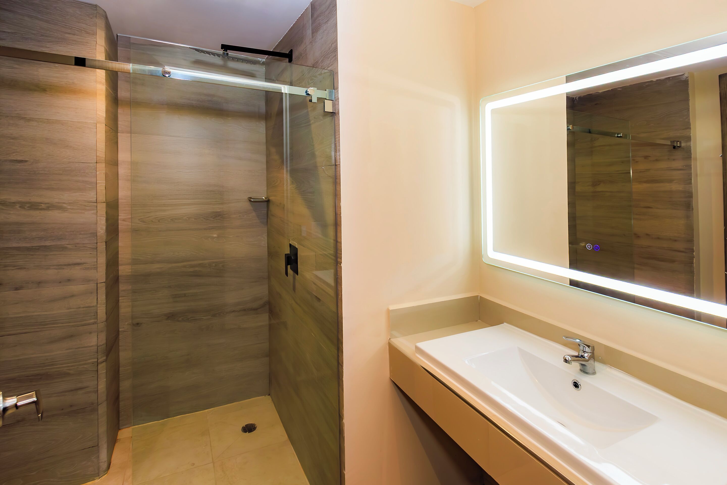 A modern bathroom with a glass-enclosed shower, a large mirror, and a white sink.
