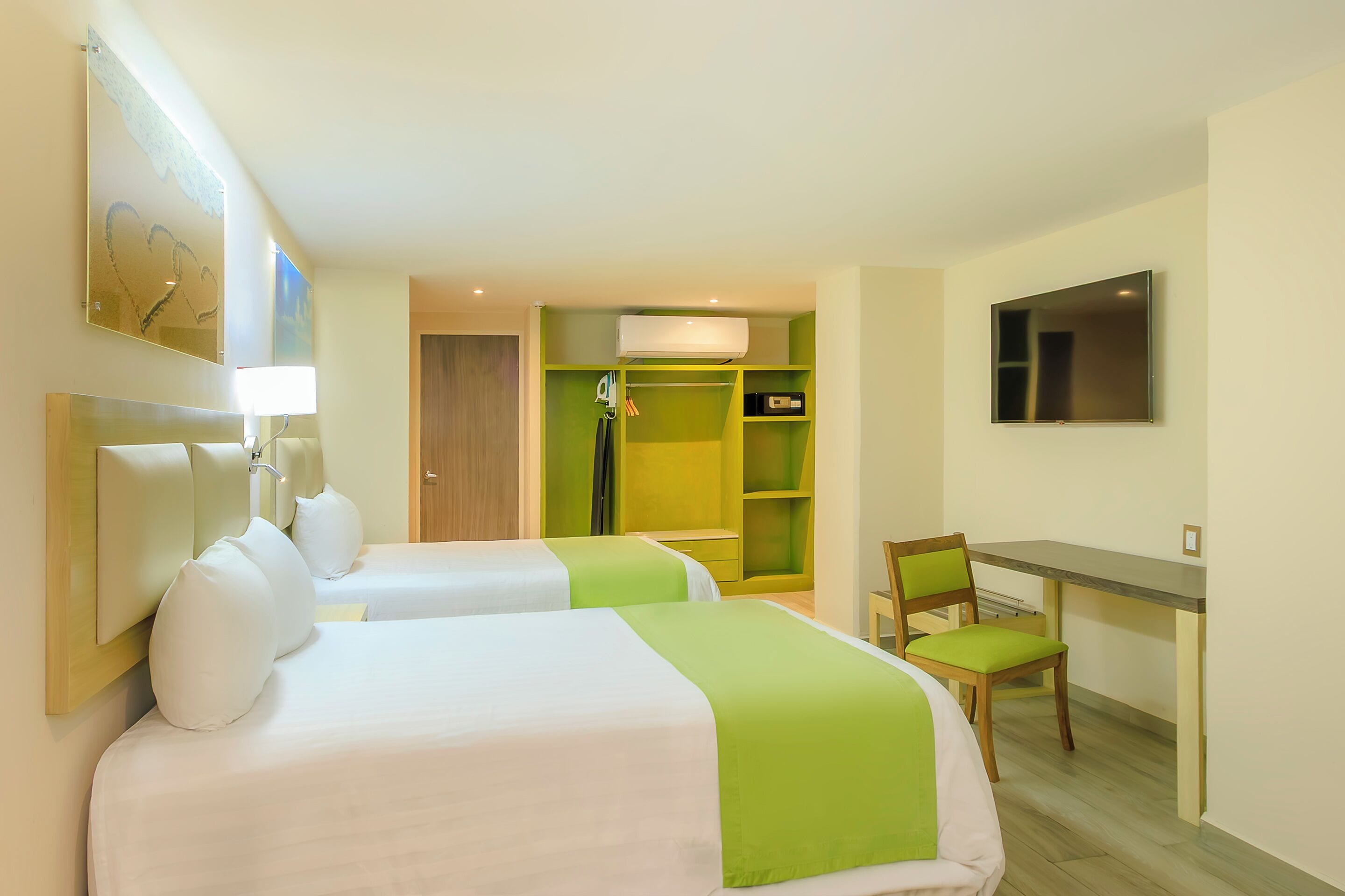 A hotel room with two beds, a desk, a chair, a TV, and a wardrobe.