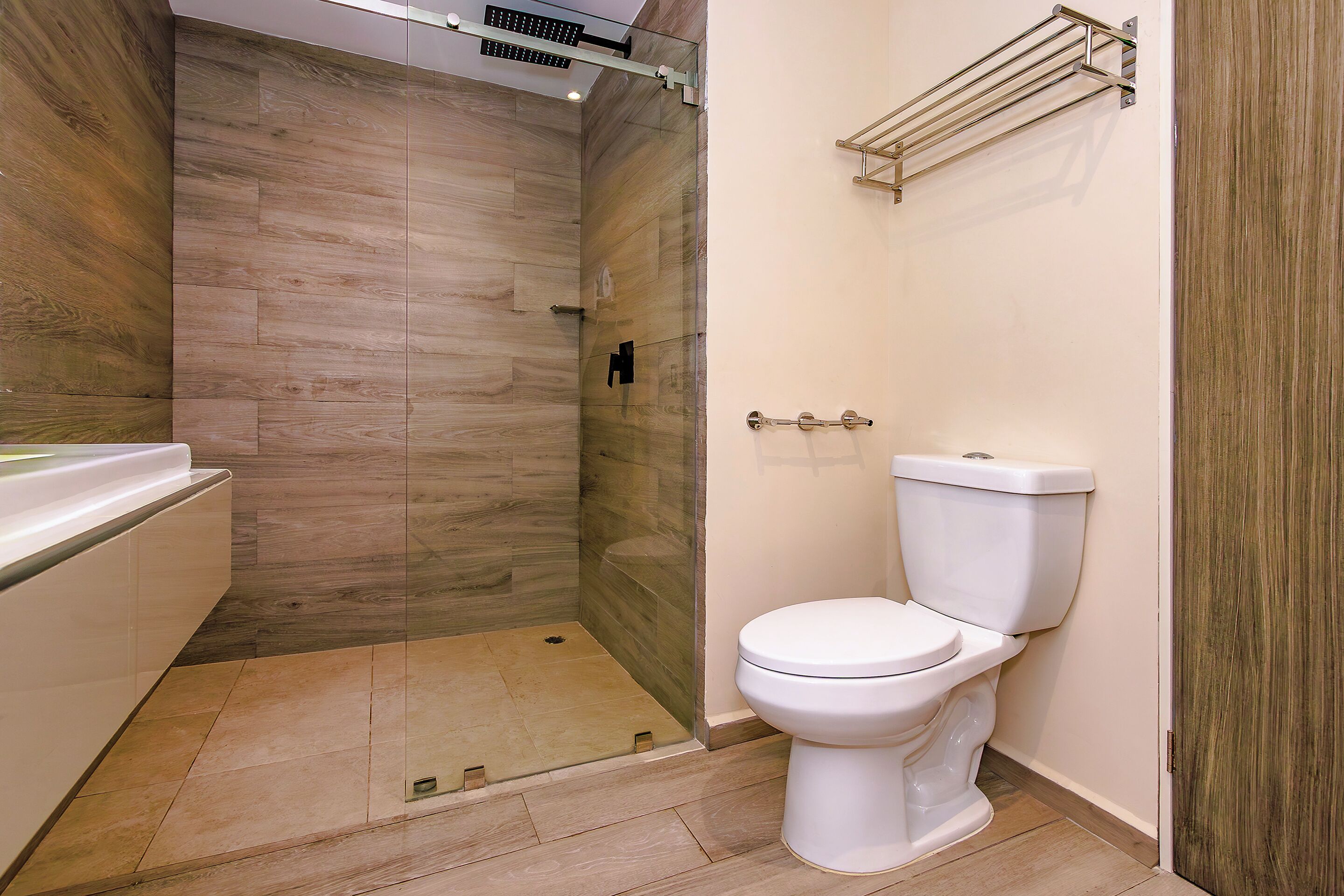 Ein modernes Badezimmer mit Duschkabine aus Glas, einer weißen Toilette und einem Holzbadezimmer-Möbelkorpus.