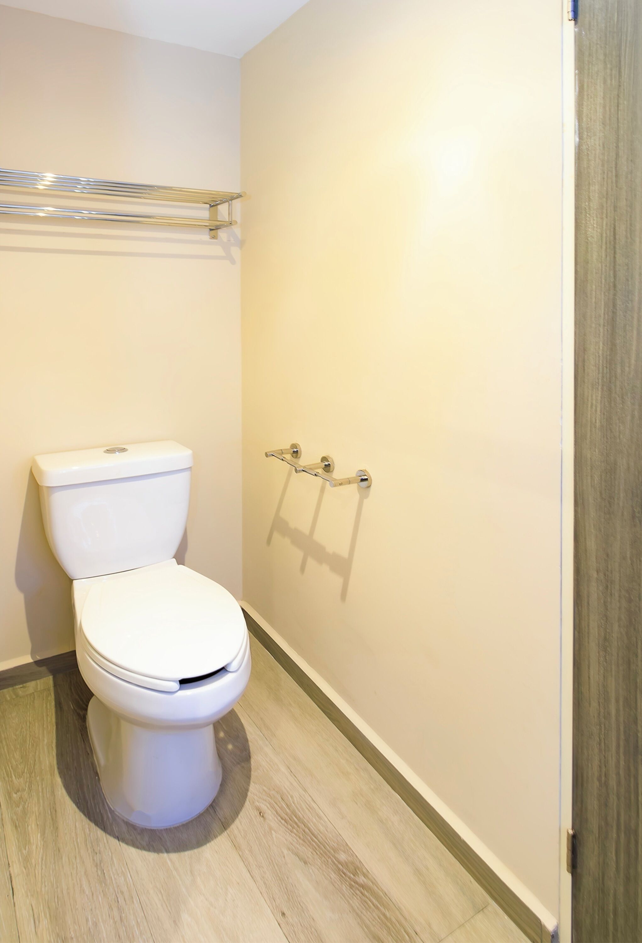 A bathroom with a toilet, a towel rack, and a shower area.