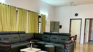 A modern living room with a sectional sofa, a coffee table, and a rug. - Casa Grey Trivandrum (Thiruvananthapuram)