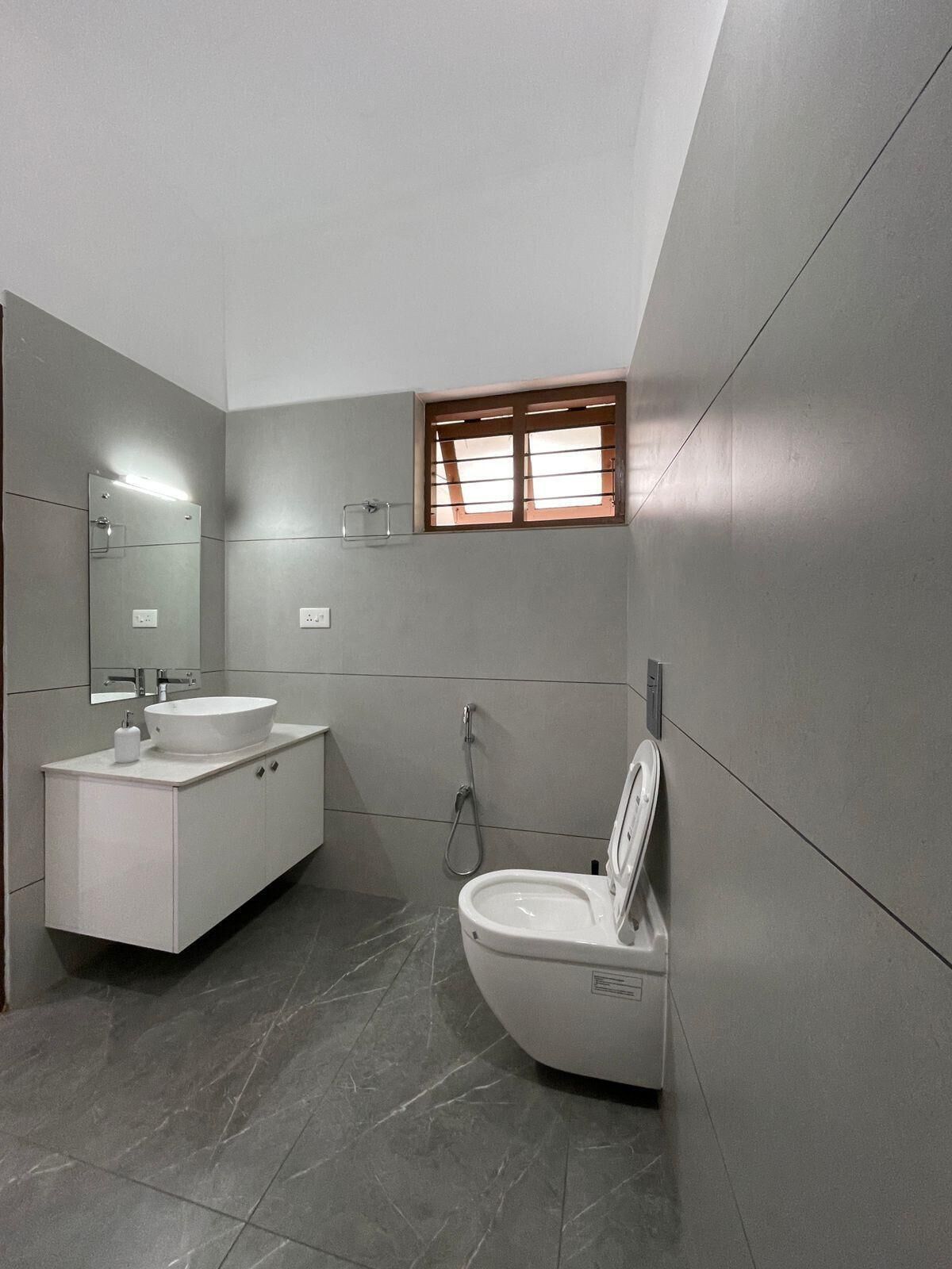 A modern bathroom with a white sink, mirror, and toilet.