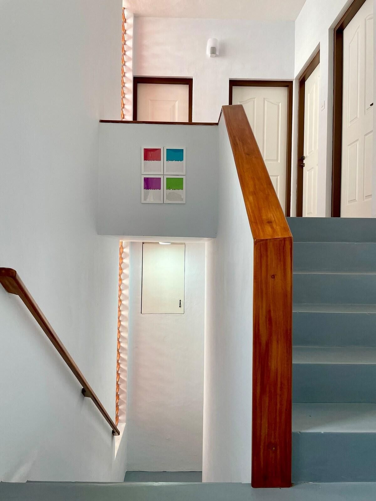 Eine Treppe mit Holzbalkonen und einer weißen Wand mit einer Tür und einem kleinen Fenster.