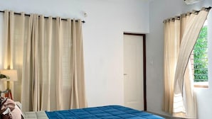 A bedroom with a bed, a desk, a ceiling fan, and curtains. - Casa Grey Trivandrum (Thiruvananthapuram)