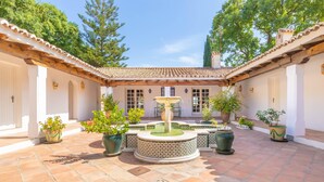 A courtyard with a fountain, potted plants, and a tiled floor. - Cortijo Villa Padierna El Lago (Benahavis)