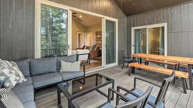 Un espace extérieur moderne aménagé avec un canapé, une table à plateau en verre et des bancs en bois.