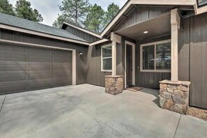 A residential garage with a concrete driveway, stone pillars, and a wooden garage door. - Gorgeous New Build, Space for Multiple Families, Hot Tub, 2 Patios and LRs (Flagstaff)