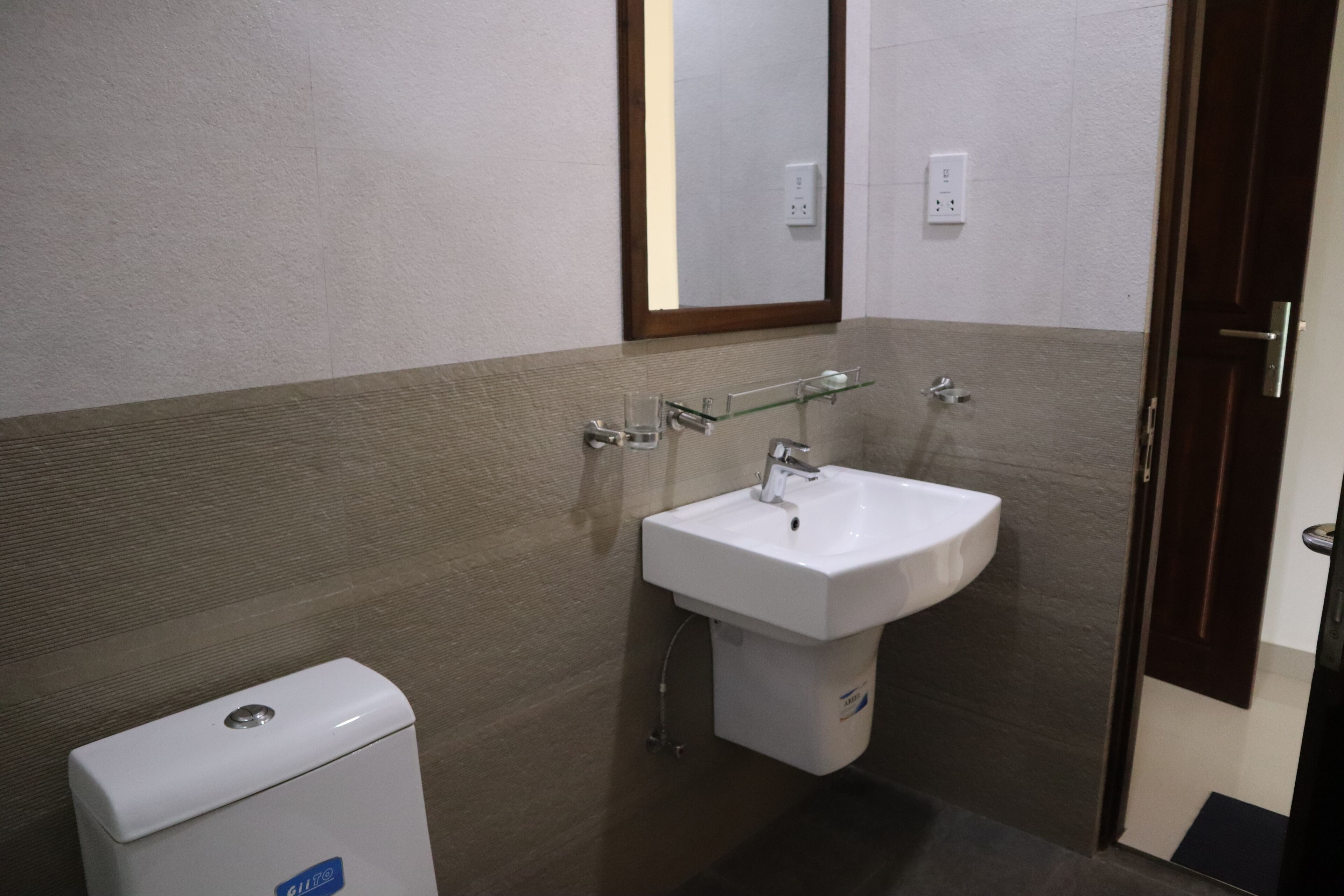 A bathroom with a white sink, a mirror, and a toilet.
