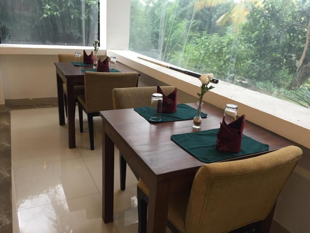 A dining area with a table set for four, a window with a view of greenery, and a vase with a single flower on the table.