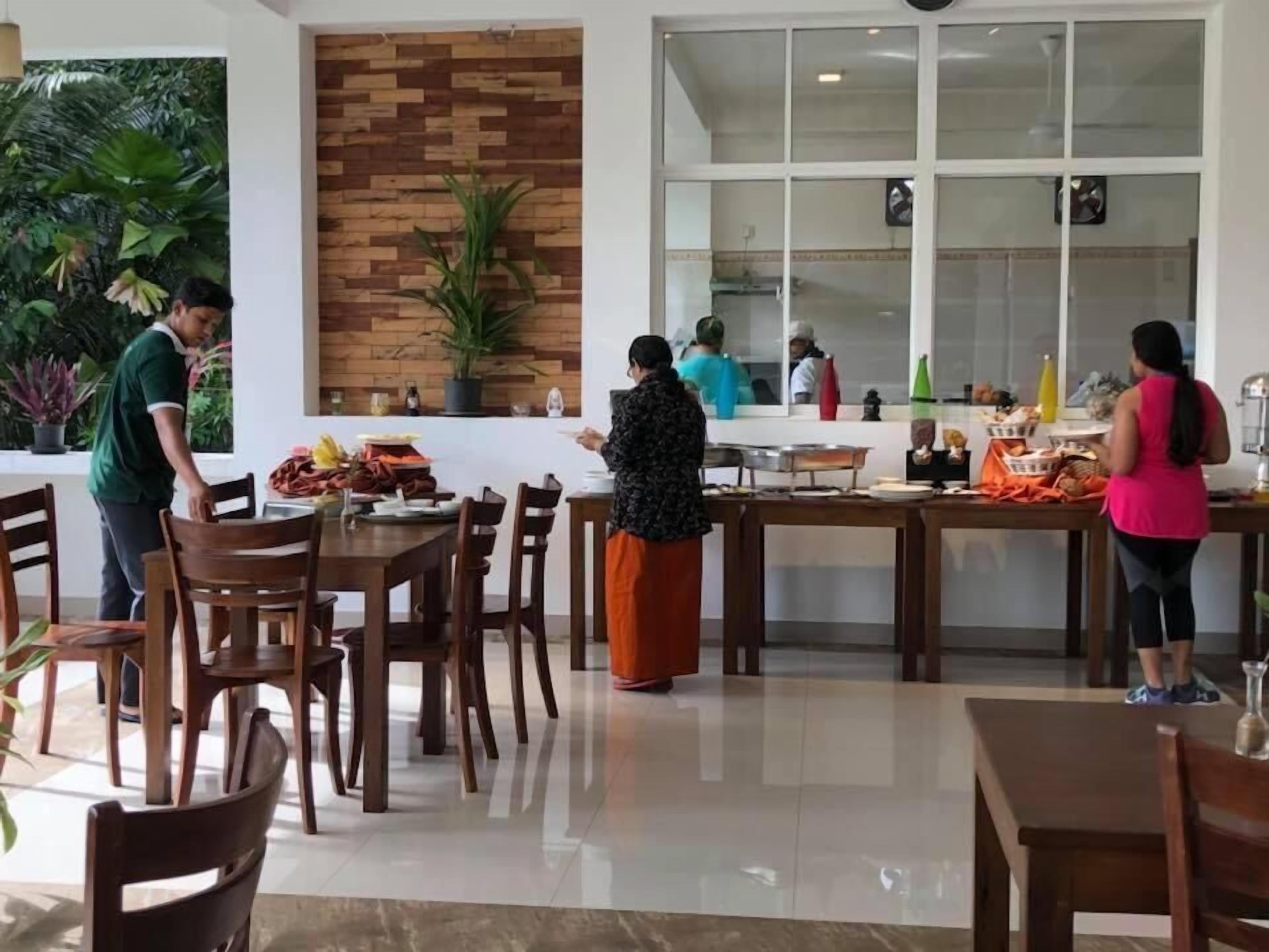 Un vaste espace dédié à la salle à manger, avec des tables et des chaises en bois, un mur en briques et de grandes fenêtres.