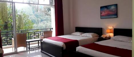 A hotel room with two beds, a balcony with a table and chairs, and a painting on the wall.