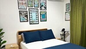Una camera da letto ordinata con un letto, comodini, un condizionatore d'aria a muro e diverse fotografie incorniciate.