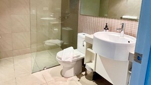 A modern bathroom with a glass shower enclosure, a white toilet, and a large sink with a mirror above it. - Pandanas Apt 8 (18th fl, Sunrise & Harbour Views) (Darwin City)