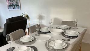 A dining table set with plates, bowls, and wine glasses, surrounded by chairs.