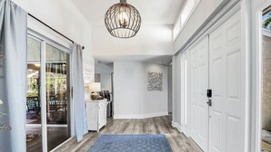 A hallway with a blue rug, white doors, and a modern pendant light.