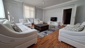 Een moderne woonkamer met twee witte banken, een salontafel en een televisie op een witte kast.