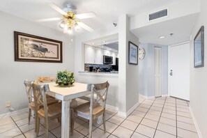 Enjoy meals in this stylish dining area with a ceiling fan, artwork, and a potted plant.