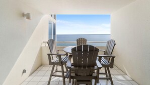 Un balcón con mesa y sillas, con vista a la playa.