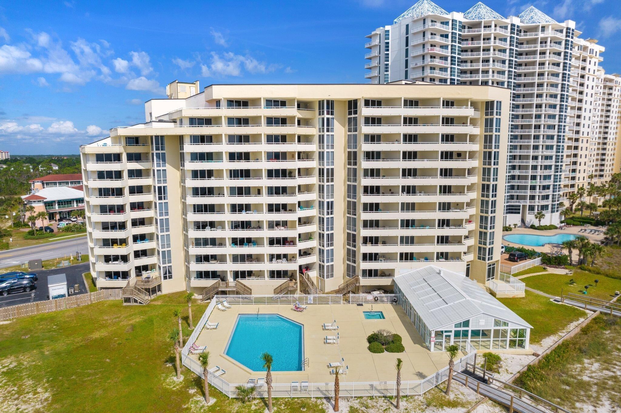 A multi-story hotel with a central courtyard pool, surrounded by balconies and a beach view.