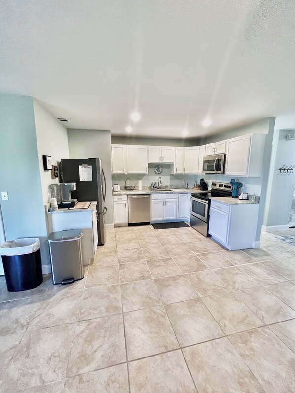 A modern kitchen with white cabinets, stainless steel appliances, and a tiled floor. - Terrific 3-bedroom house in charming Sebastian with AC, WiFi (Sebastian)