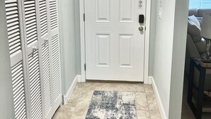Un pasillo con una puerta blanca, un tapete estampado y una decoración de pez en la pared.