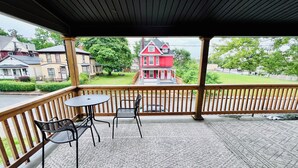 Ein überdachter Außenbereich mit Holzbalkon, einem Tisch und zwei Stühlen.