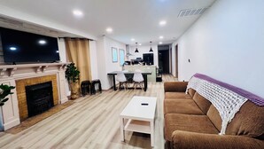 Ein modernes Wohnzimmer mit Kamin, Essbereich und einer Küche im Hintergrund.