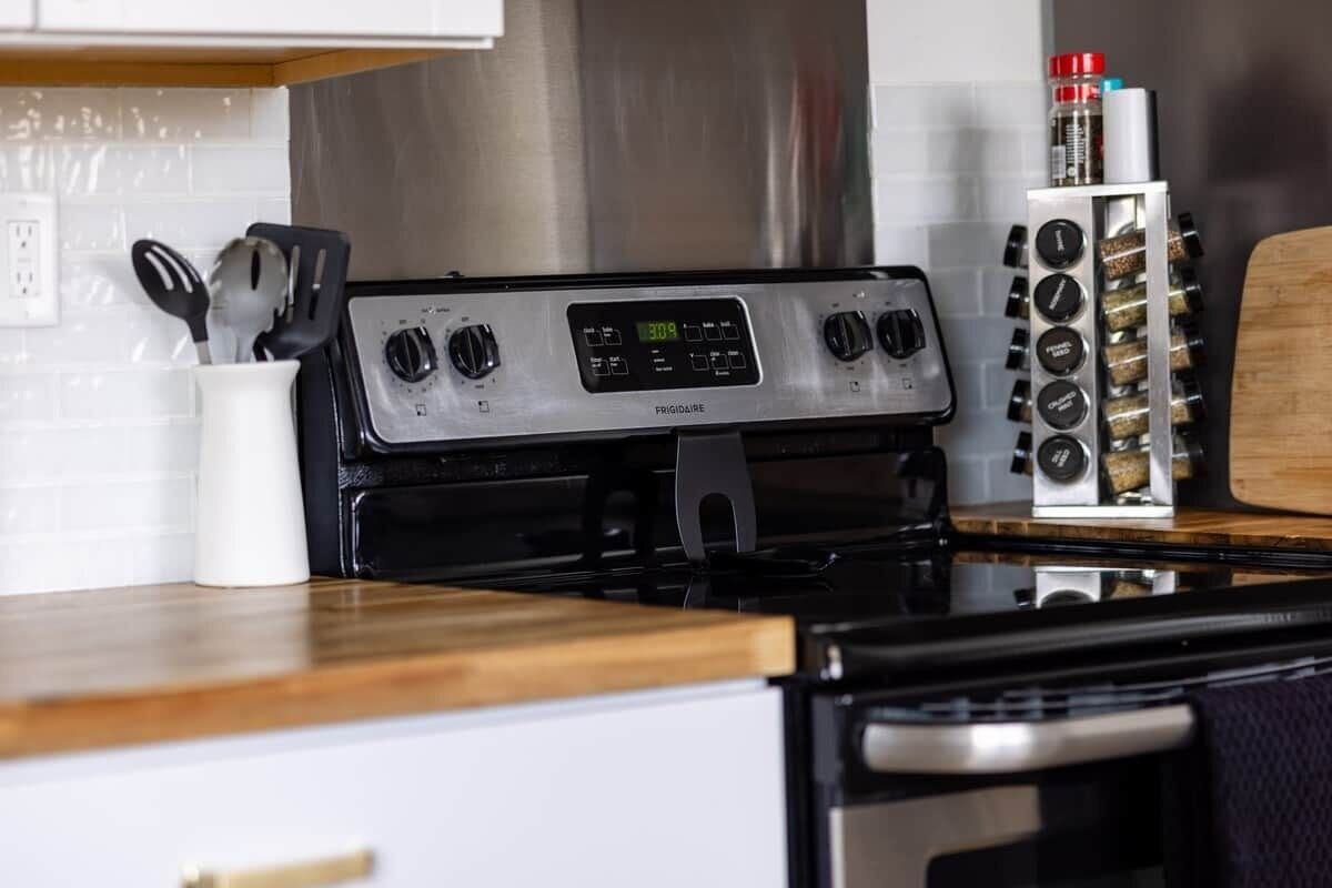 Una cucina con un fornello, una spezieria e una macchina per il caffè.