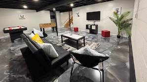 Una sala de estar moderna con una mesa de fútbol, un sofá, una mesa de centro y un televisor.