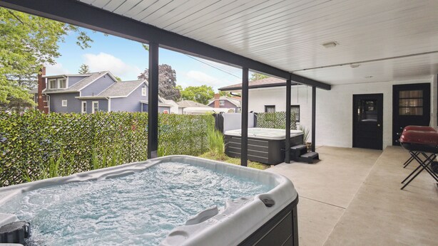 Un jacuzzi en un área exterior techada con vista a casas vecinas.
