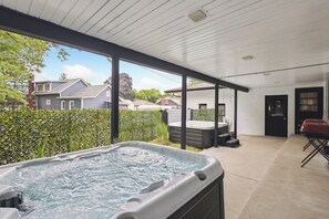 A hot tub in a covered outdoor area with a view of neighboring houses.
