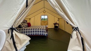 A tent with a bed, a small table, and a window. - “Queen's Quarters” Cozy Outdoor Glamping • Hot Tub (Monument)