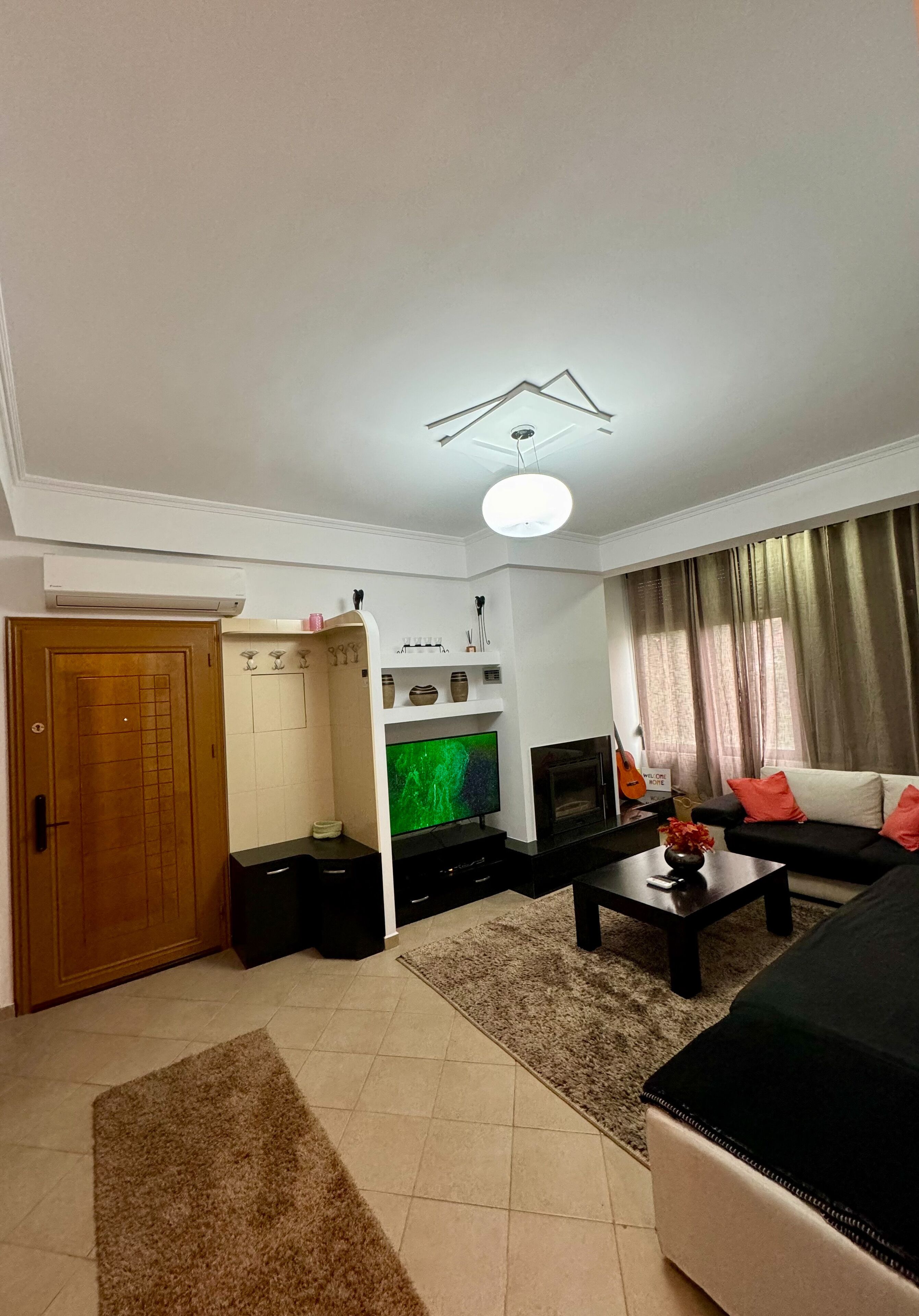 Ein Wohnzimmer mit einer Couch, einem Couchtisch, einem Fernseher, einem Kamin und einer Tür.