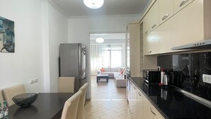 Ett modernt kök med matplats, med en svart bänkskiva, beige skåp och ett golv med fiskbensmönster.