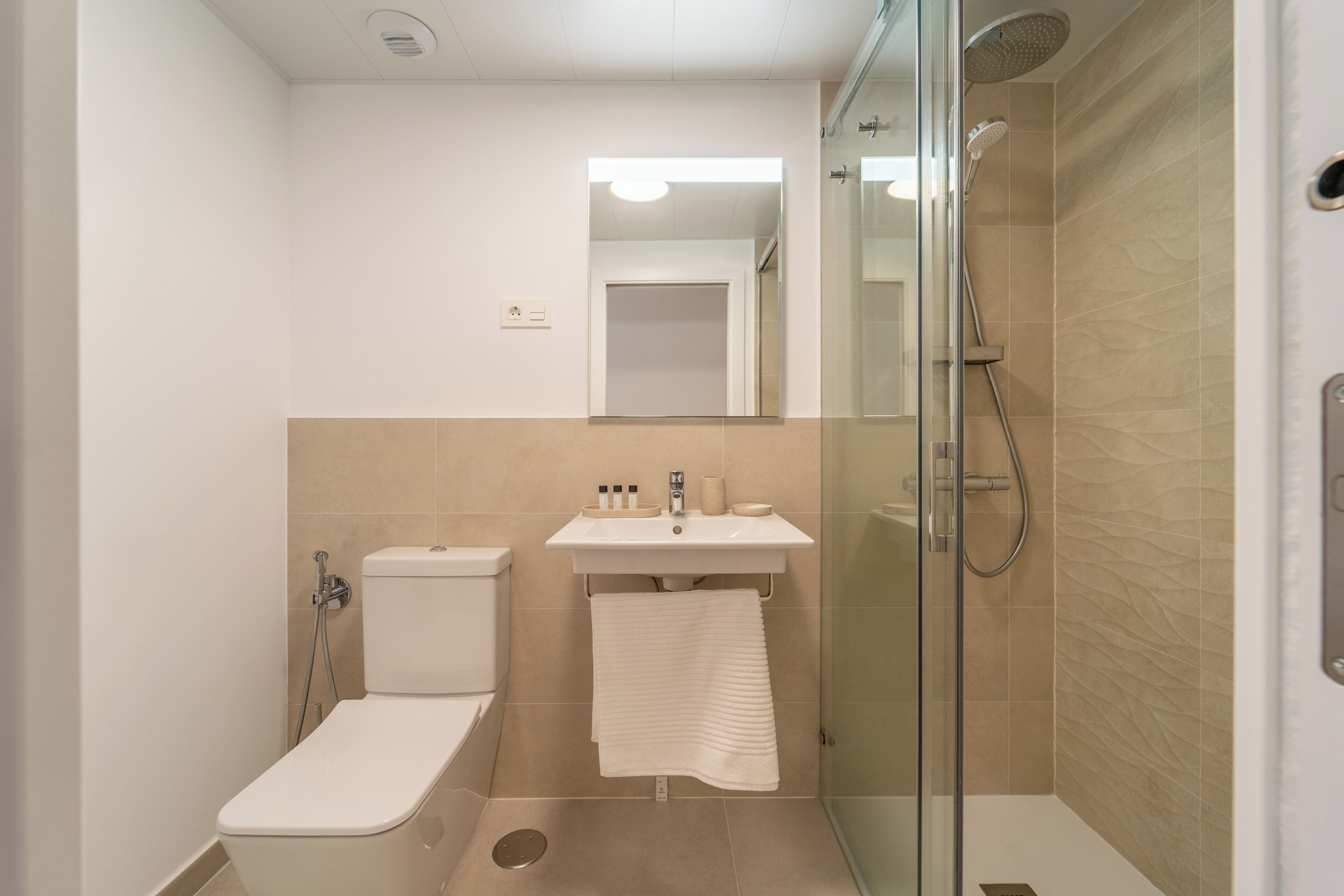 Une salle de bain moderne équipée de toilettes, d’un lavabo et d’une douche à parois de verre.