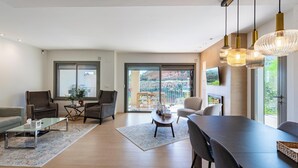 Un soggiorno spazioso con un grande tavolo da pranzo, comodi posti a sedere e vista su un balcone con un paesaggio suggestivo.