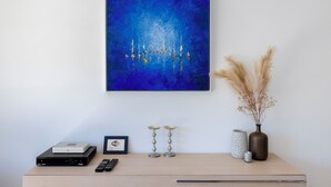 Una habitación con un cuadro abstracto azul, un escritorio de madera con un router, un control remoto y objetos decorativos.