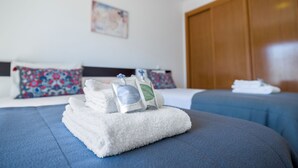 Una habitación de hotel con dos camas, un armario de madera y un cuadro en la pared.