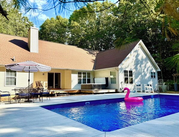 Een huis met een zwembad, een overdekt terras en een roze flamingo drijver.