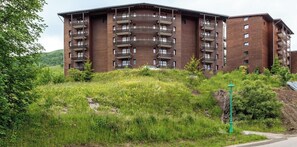 Un immeuble à plusieurs étages doté de balcons, entouré de verdure.