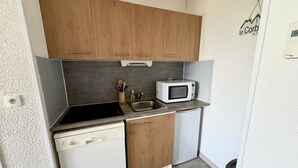 A compact kitchen with wooden cabinets, a microwave, a dishwasher, and a sink. - Le Nid des 3 Sommets - Proche station de ski (Villarembert)